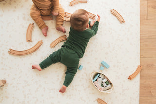 Two babies playing on a neutral padded play mat