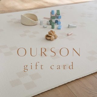 Neutral wooden toys on a padded reversible single piece play mat with a beige neutral taupe squares design. Text across the image reads OURSON gift card.